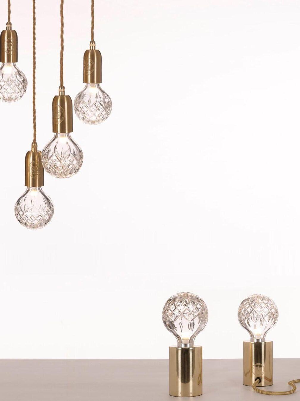 Five hanging globe lights above two clear globe table lamps