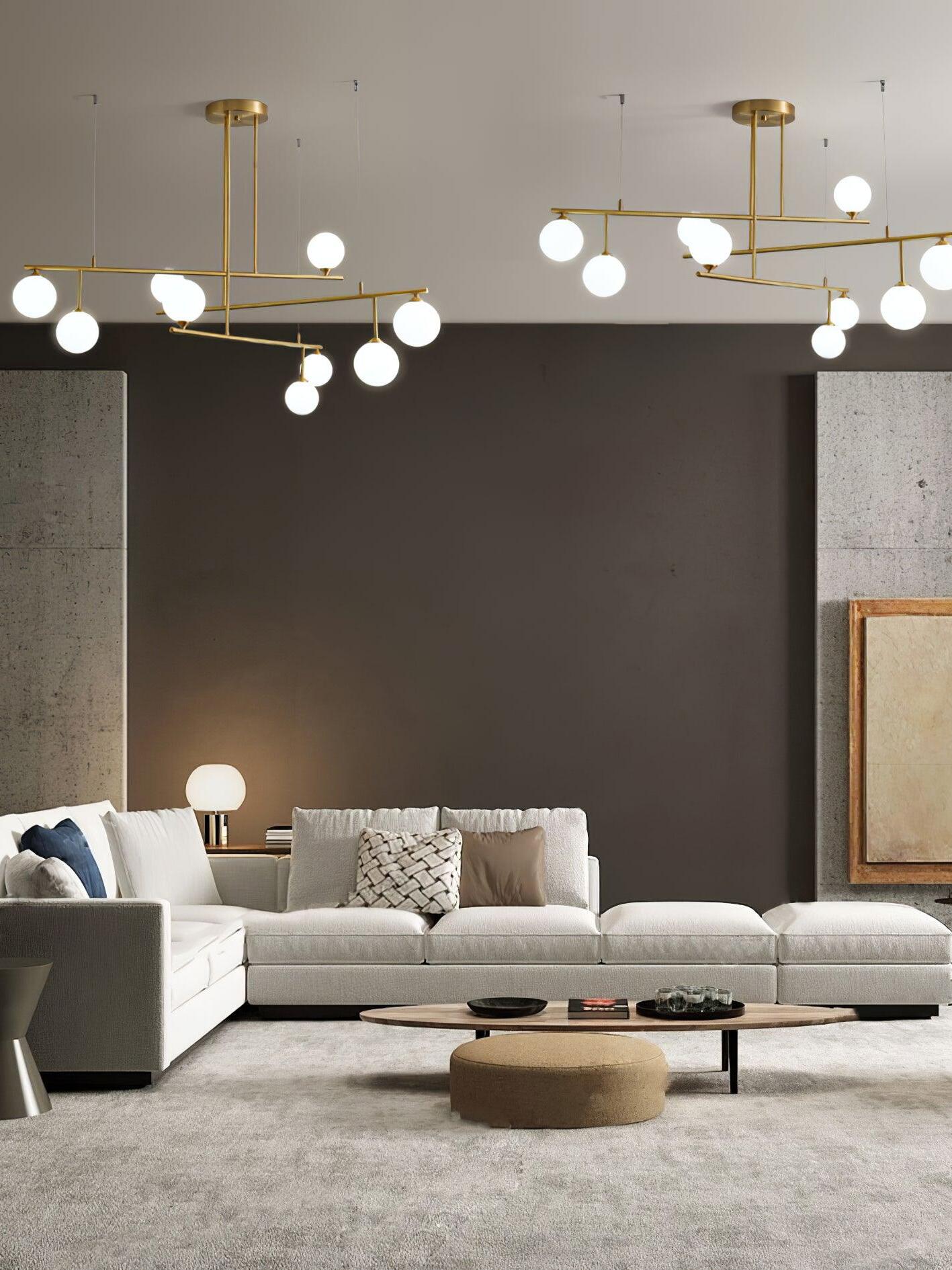 Two separate Arteriors globe chandeliers shown above a pale sofa and low round coffee table