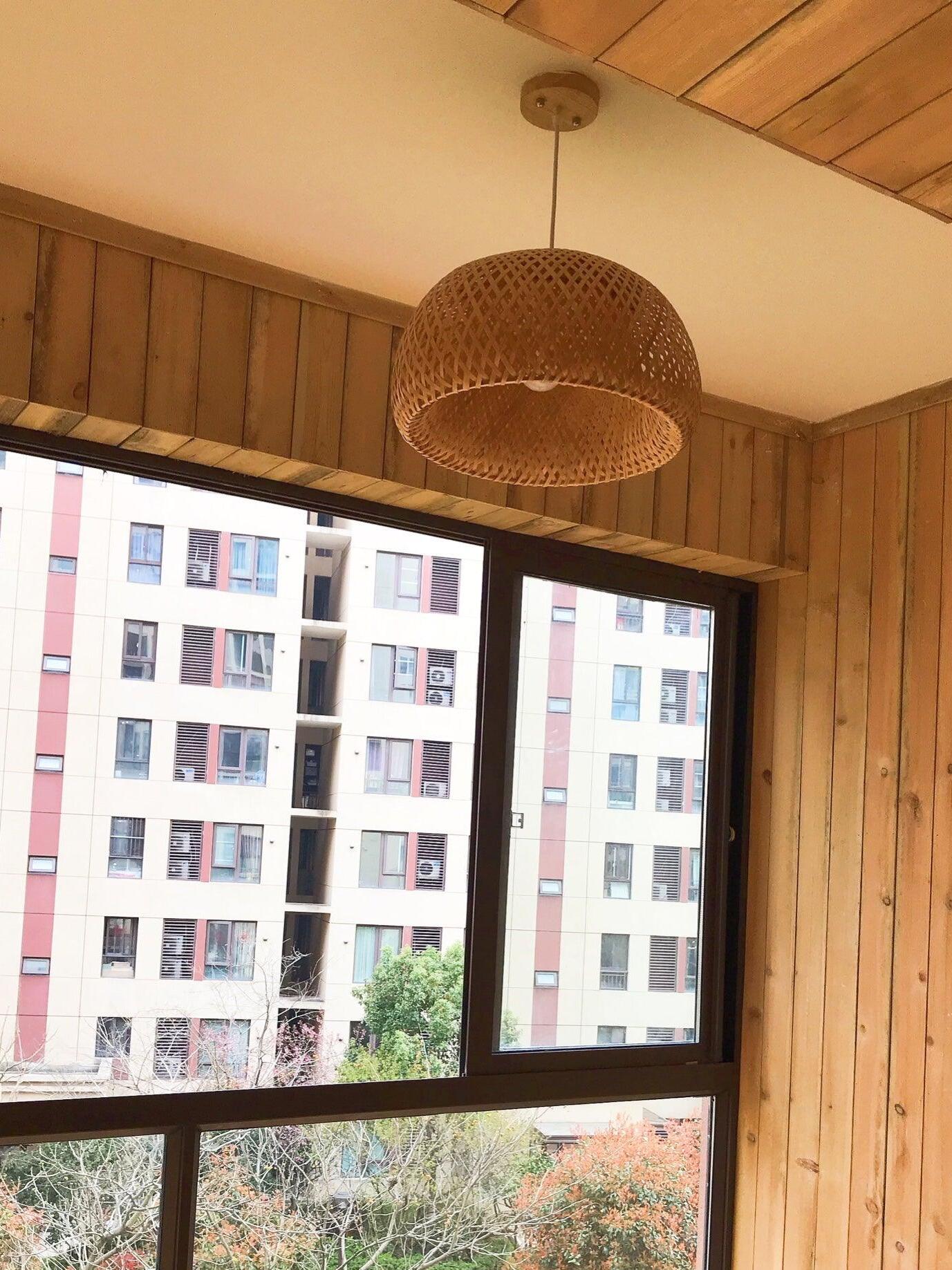 Woven pendant beside large window and timber wall
