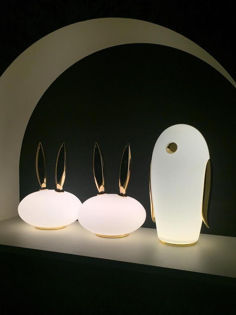 Two rabbit-shaped lamps and penguin beneath arch in dim room