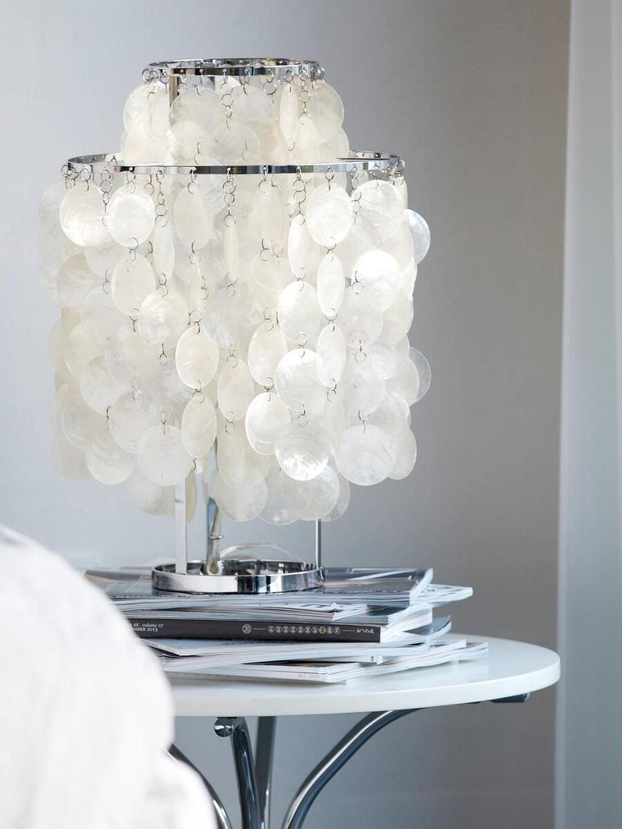Chrome-tone shell lamp on stacked books on round side table