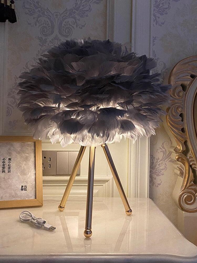Grey feather shade on gold tripod beside frame