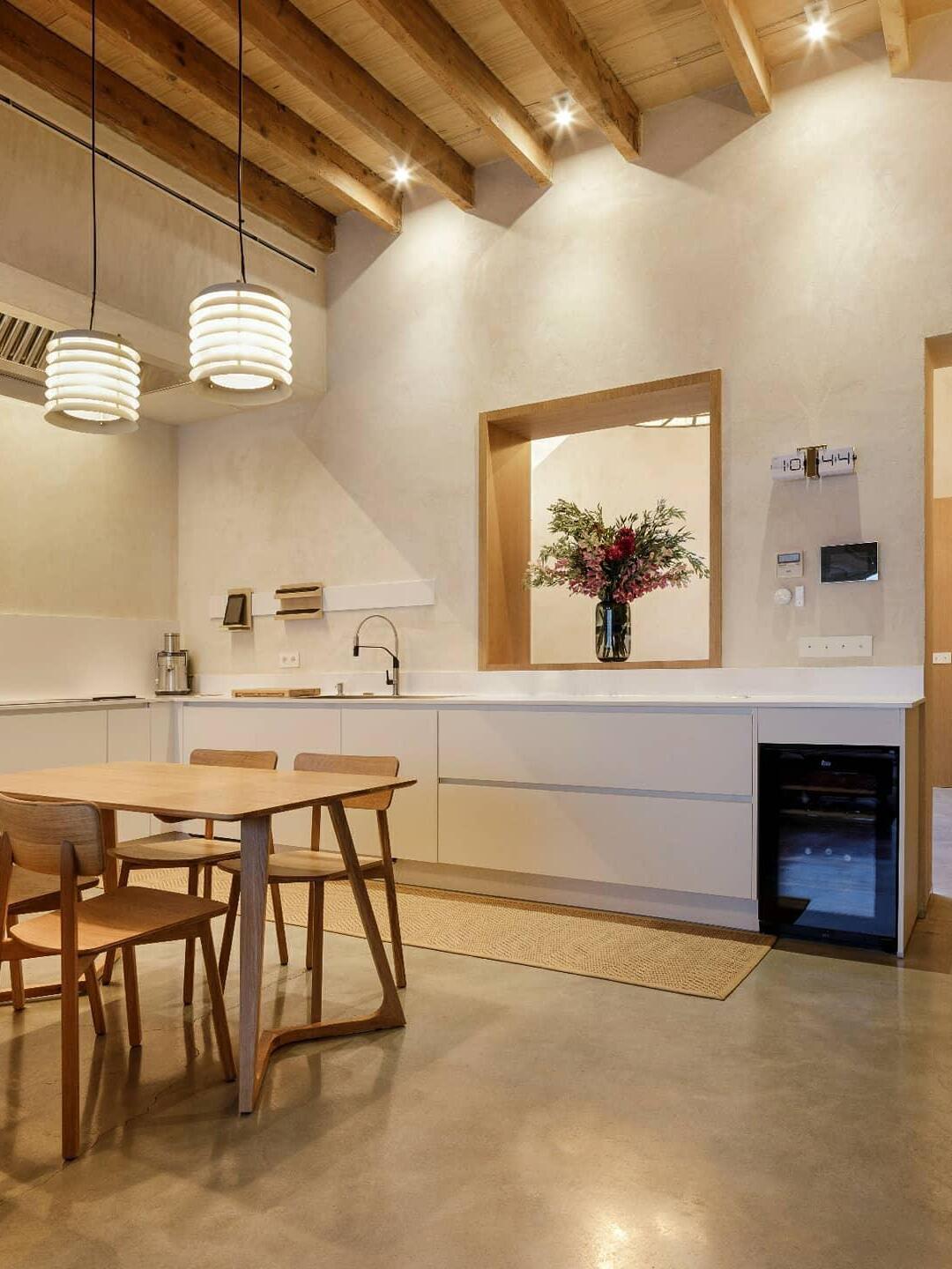 Pair of lit white stacked pendants above table in wood-beamed room
