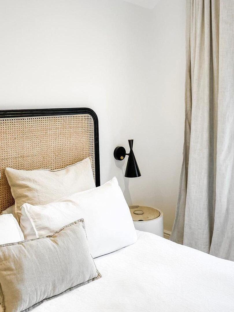 Black conical wall sconce beside white pillows and curtains