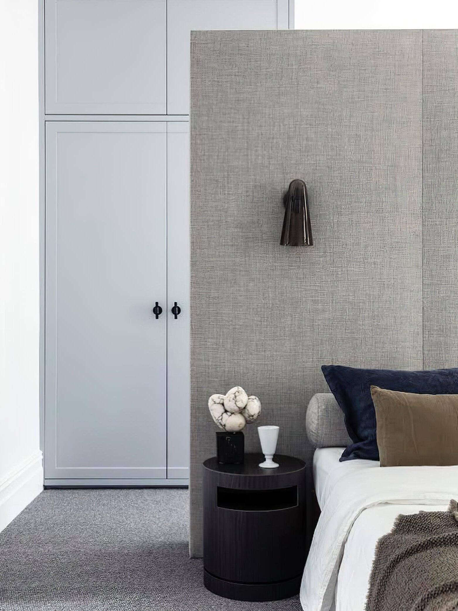 Dark-toned wall shade beside an upholstered bed