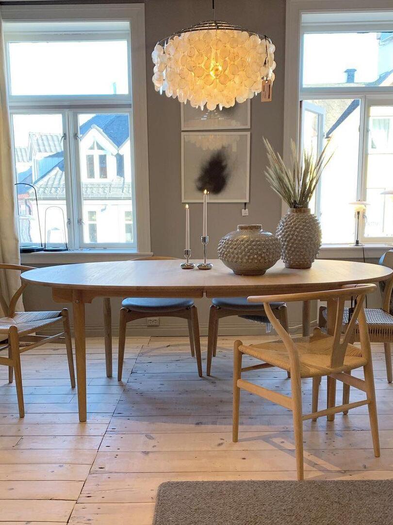 Glowing shell chandelier above a dining table by windows