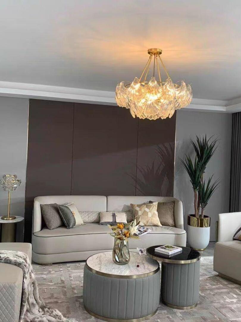Warm-looking glass light above a gray sofa and fluted round coffee tables in a paneled room