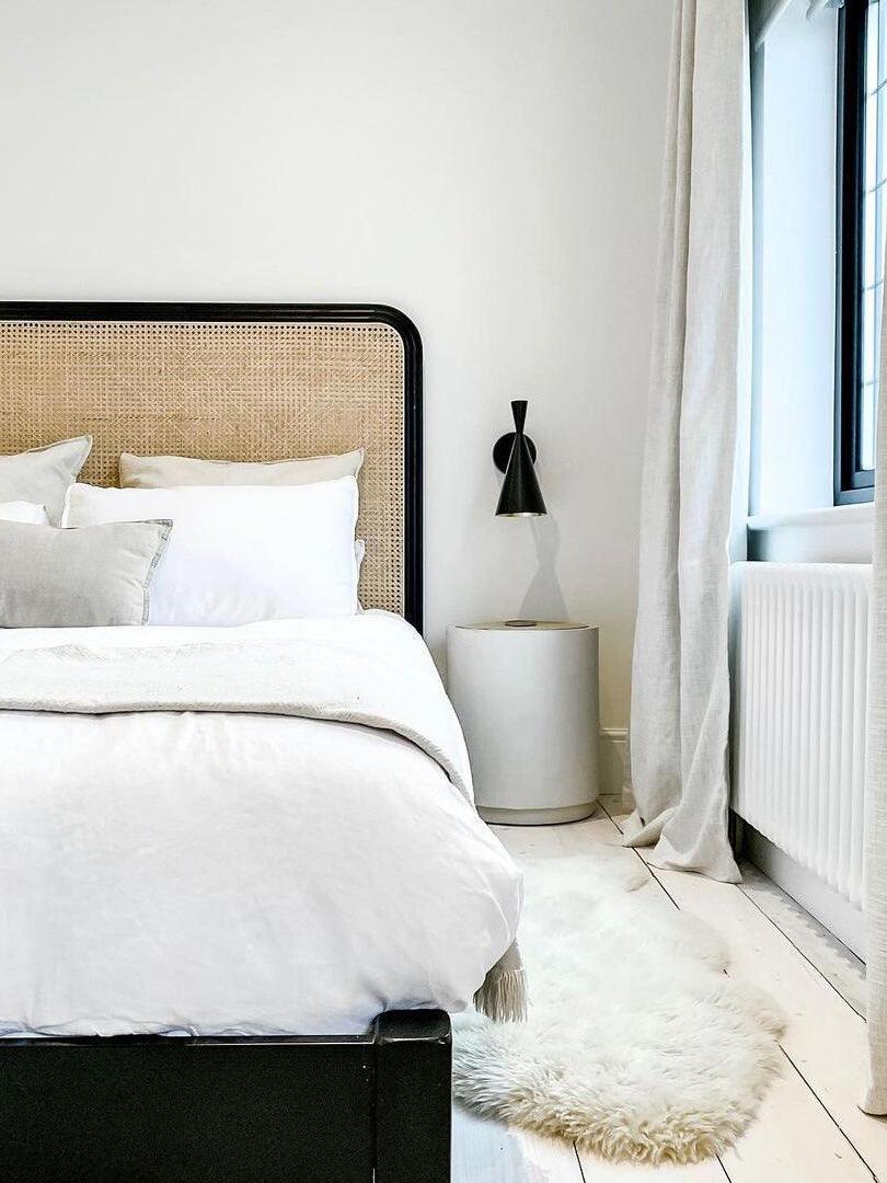 Single black wall light beside a bed near a window