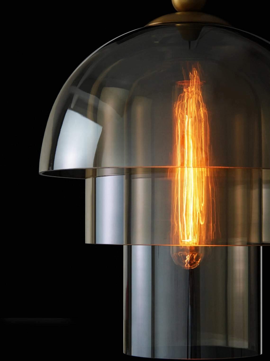 Lit filament bulb visible through a three-tier glass shade against black, with reflections on the domed surface