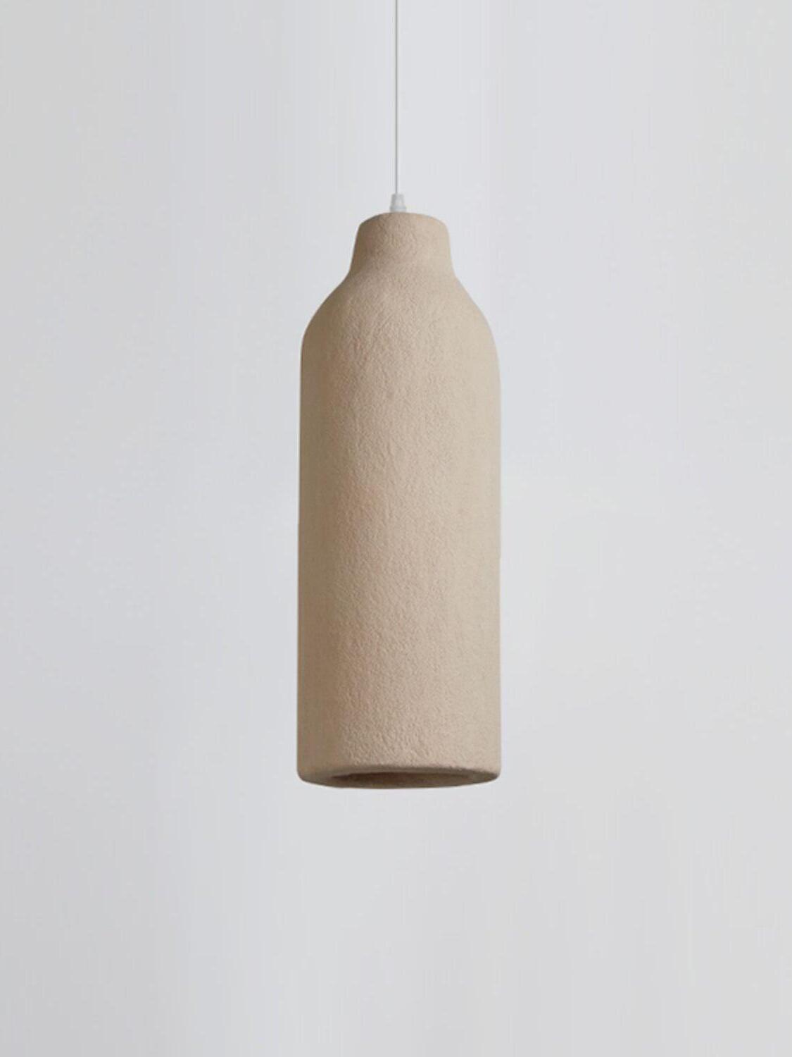 Unlit narrow bottle-shaped pendant with a rough pale surface and dark lower opening on white