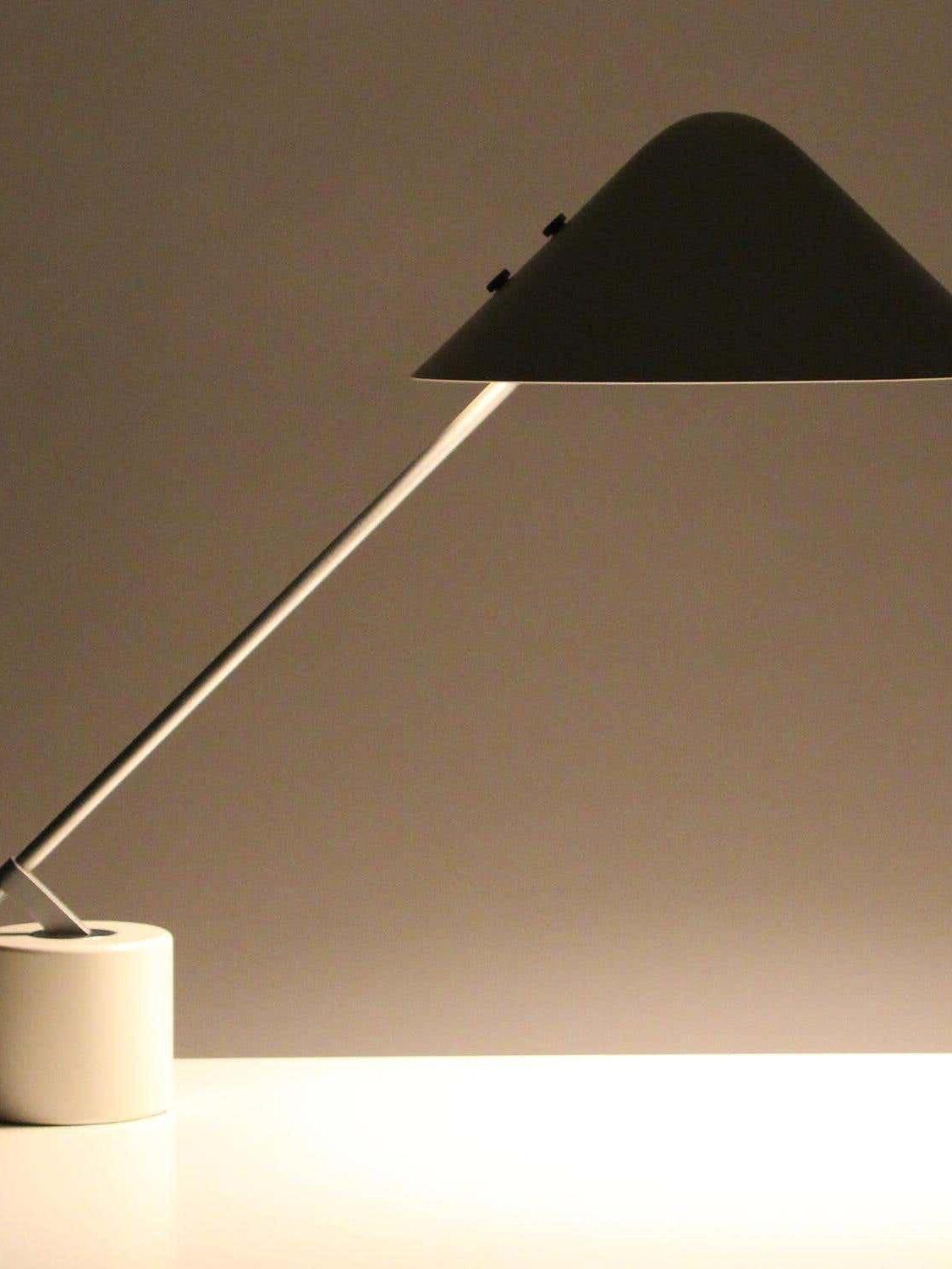 Dark-looking angled shade and silver-tone arm above a brightly lit tabletop