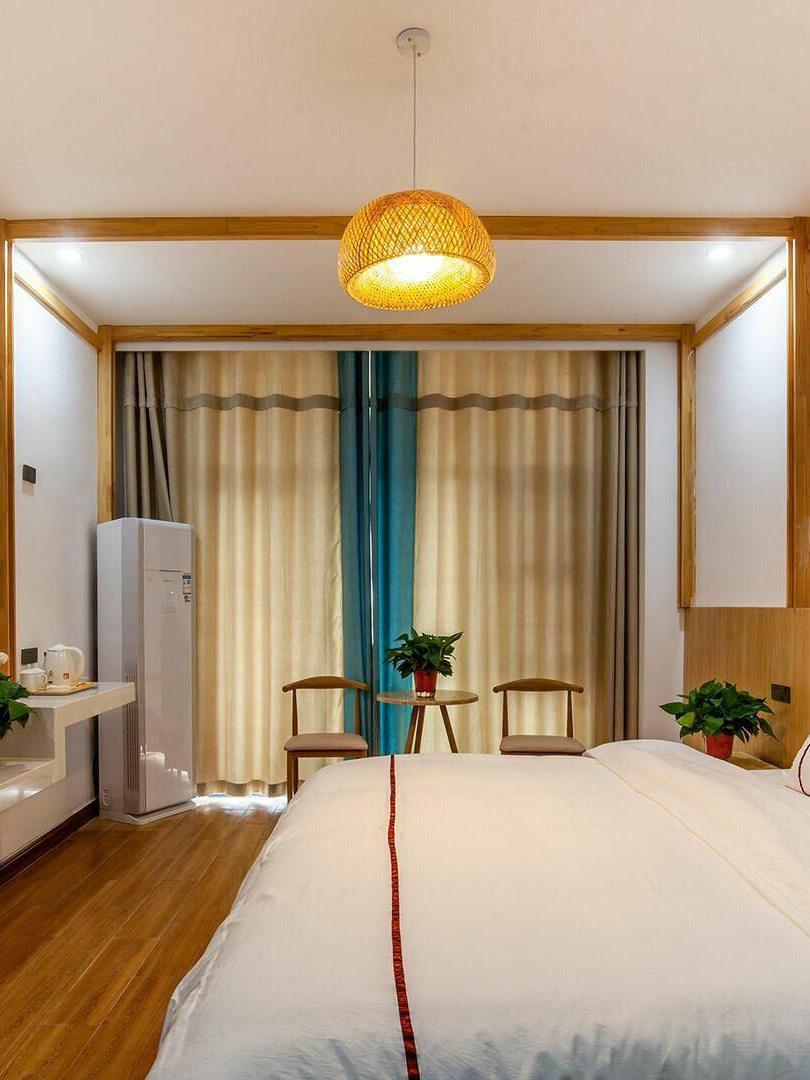 Lit woven pendant centred above a bed in a timber room