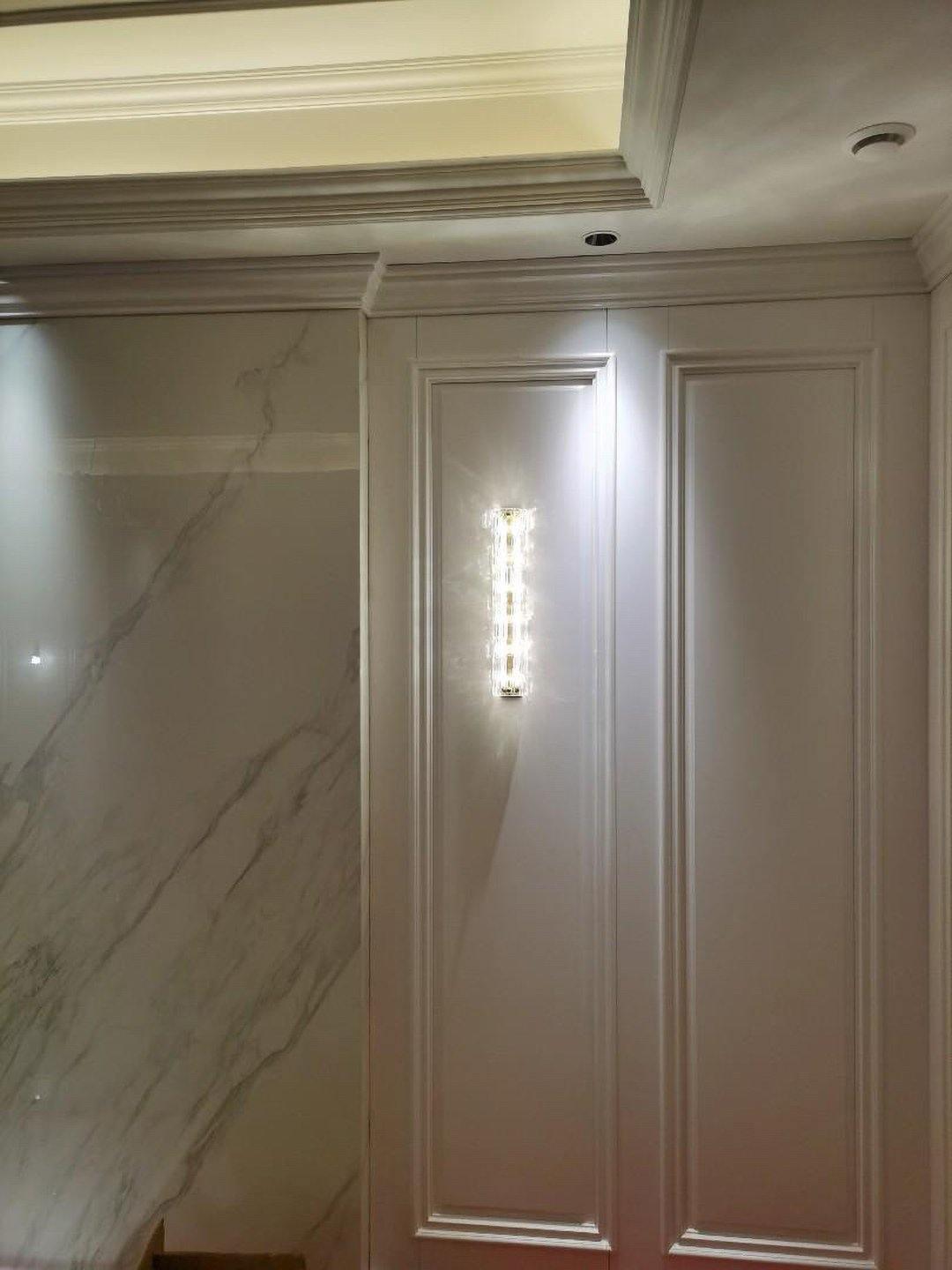 Glass wall light on white panel near ceiling cornice