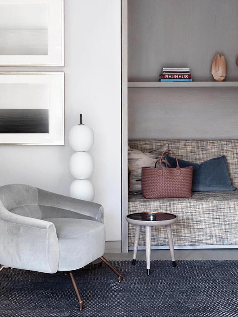 White globe lamp beside pale chair and fireplace
