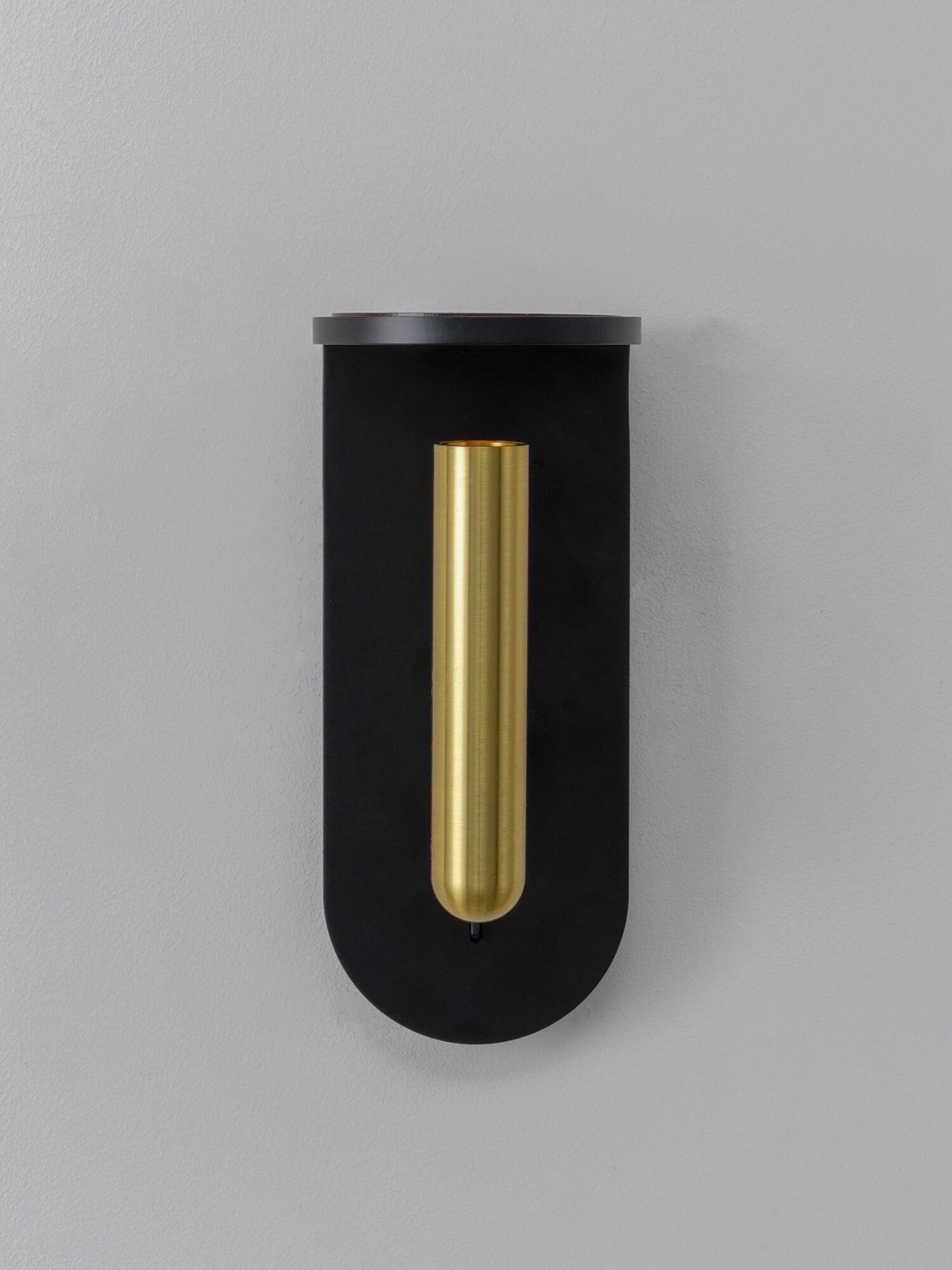 Front view of the black Nights wall light with its head vertical against the rounded backplate