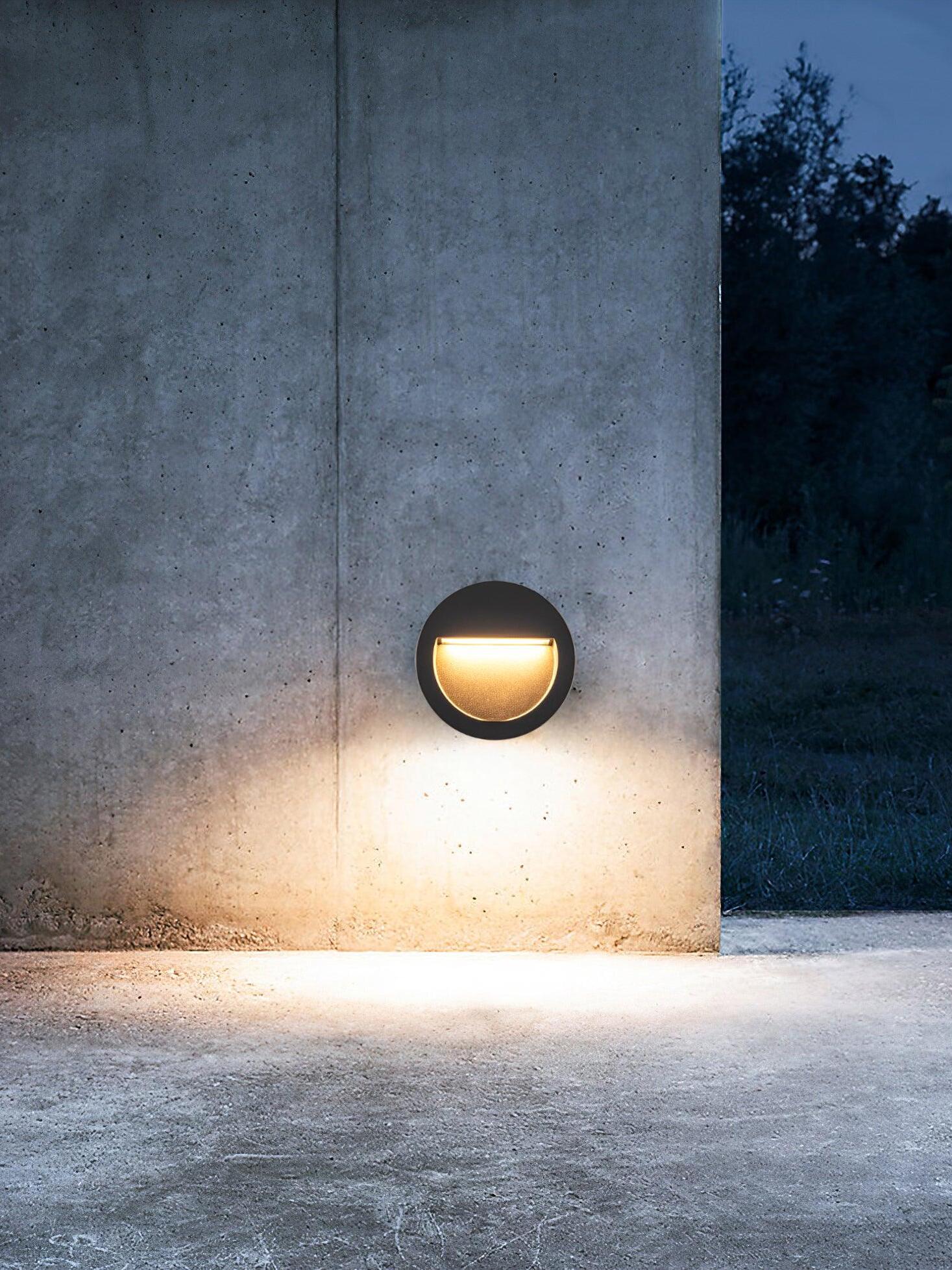 Round black light on concrete wall at dusk