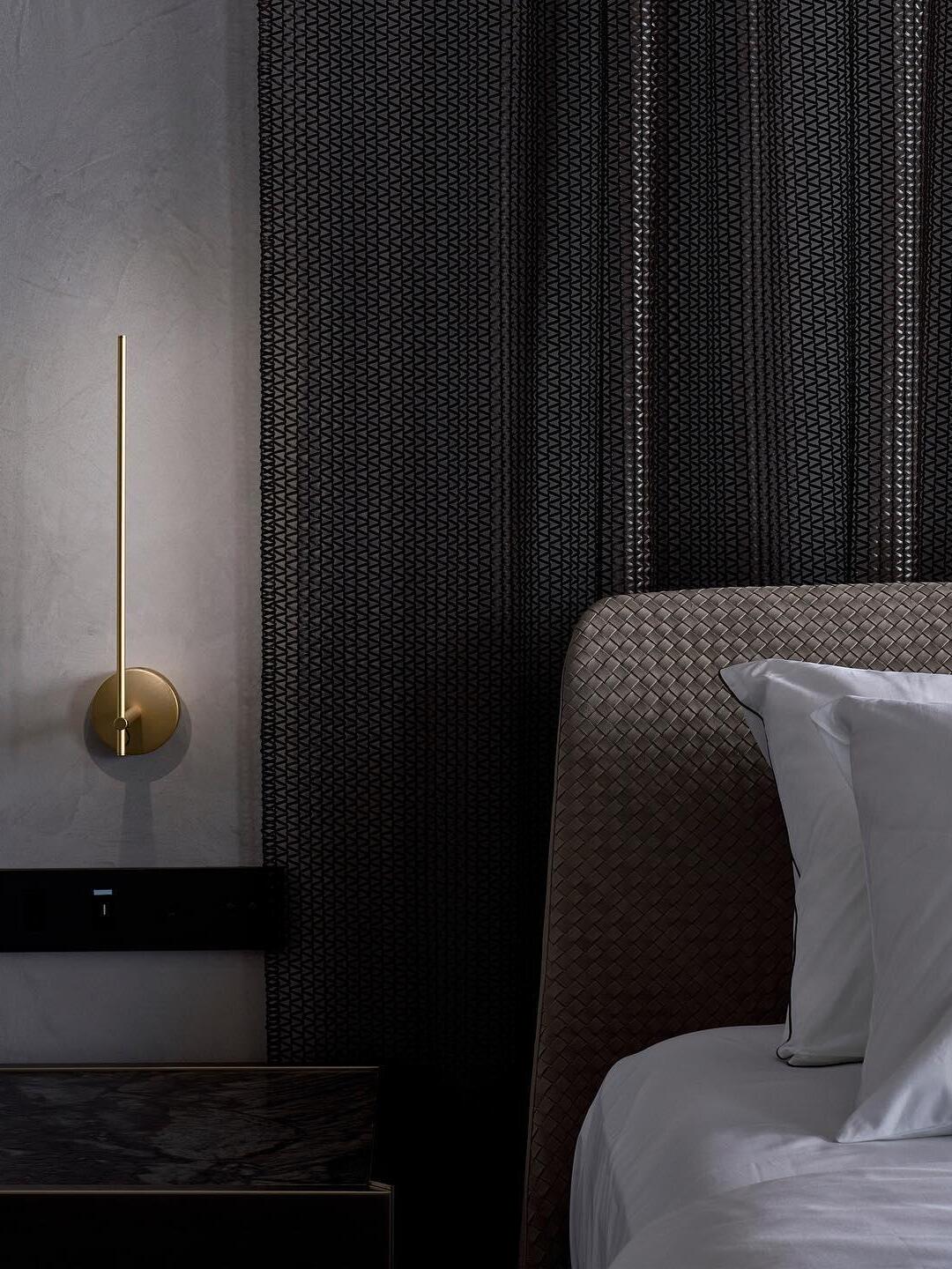 Gold vertical sconce at a bedside