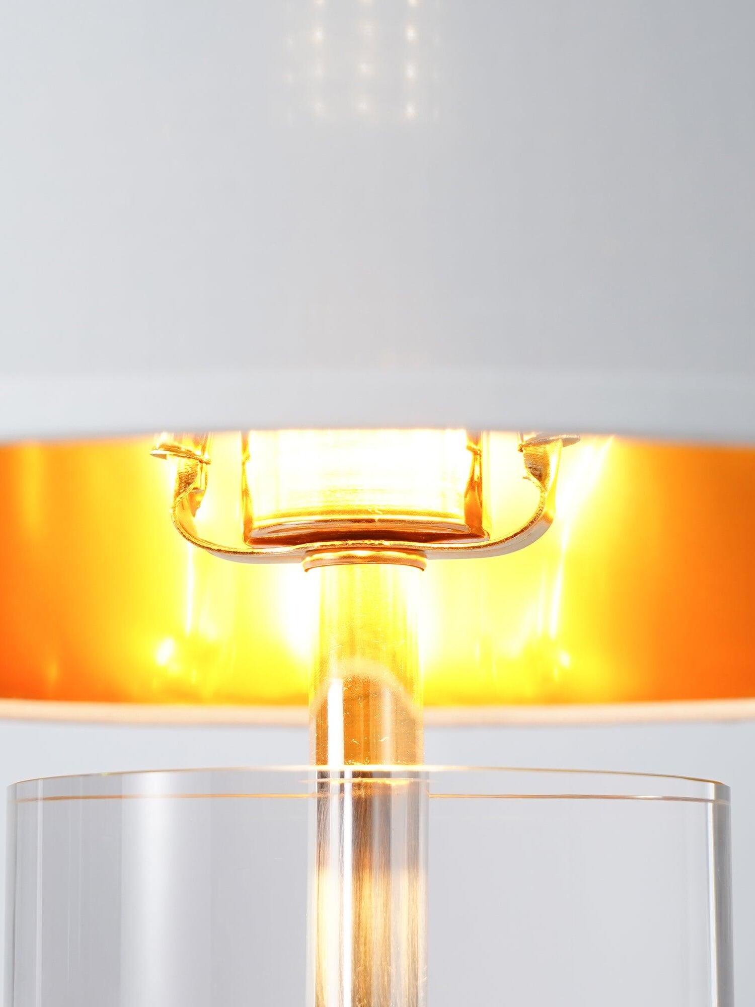 Close illuminated shade underside and holder hardware above clear cylindrical collar