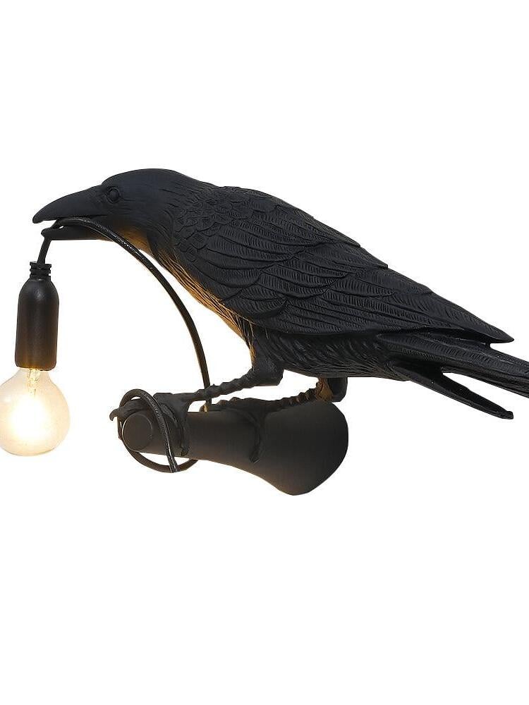 Black bird close-up with a partially cropped lit bulb, cylindrical wall bracket and looped cord