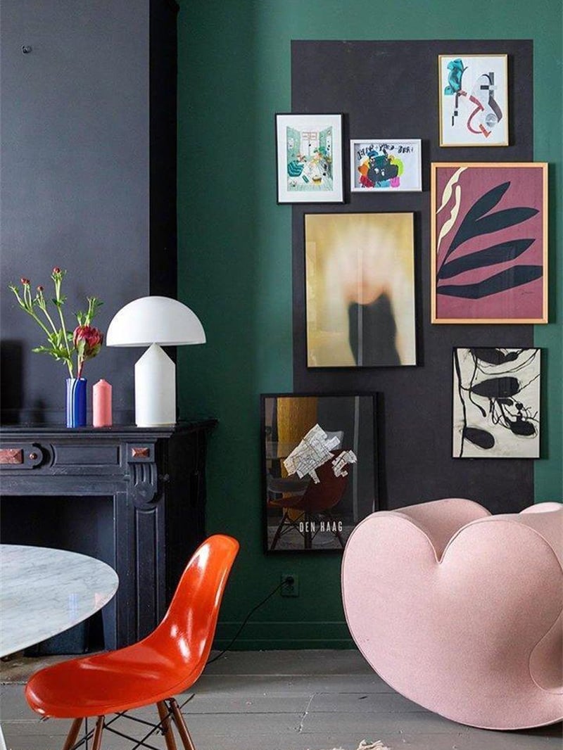 White mushroom lamp on a dark mantel near flowers and a pink candle, with framed art on a green wall