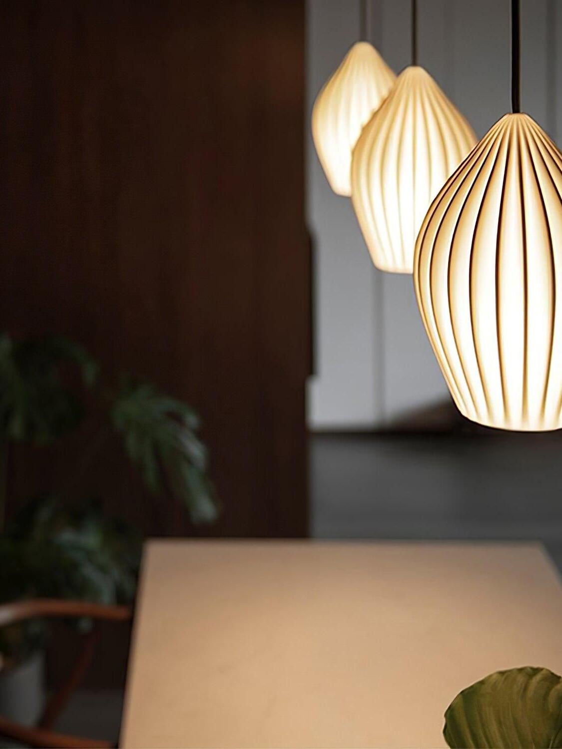 Angled close-up of three glowing ribbed shades suspended above a pale table