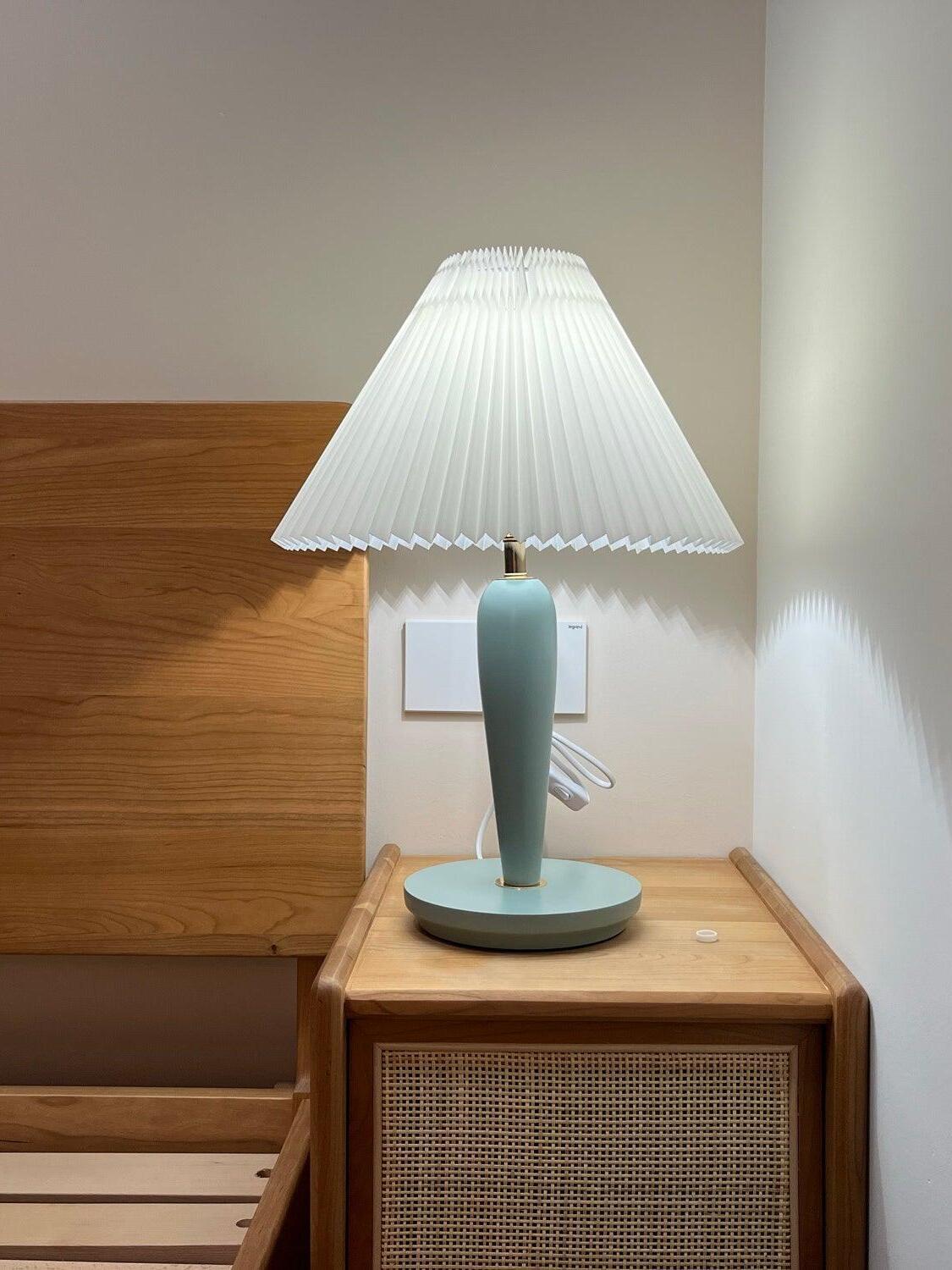 Light-blue lamp with white shade on cane-front cabinet