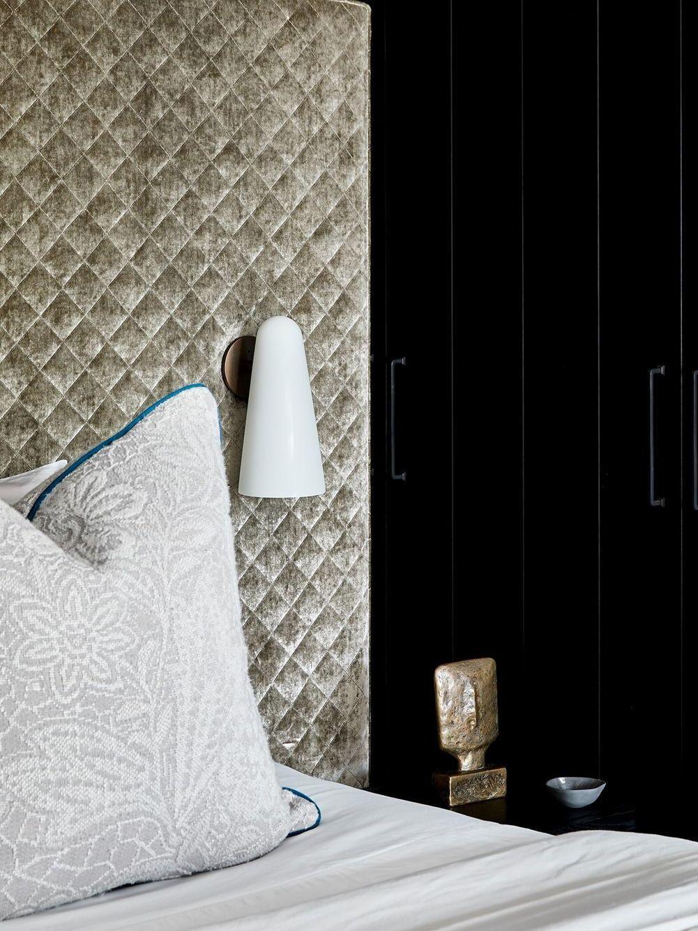 Pale conical wall shade beside patterned bedding