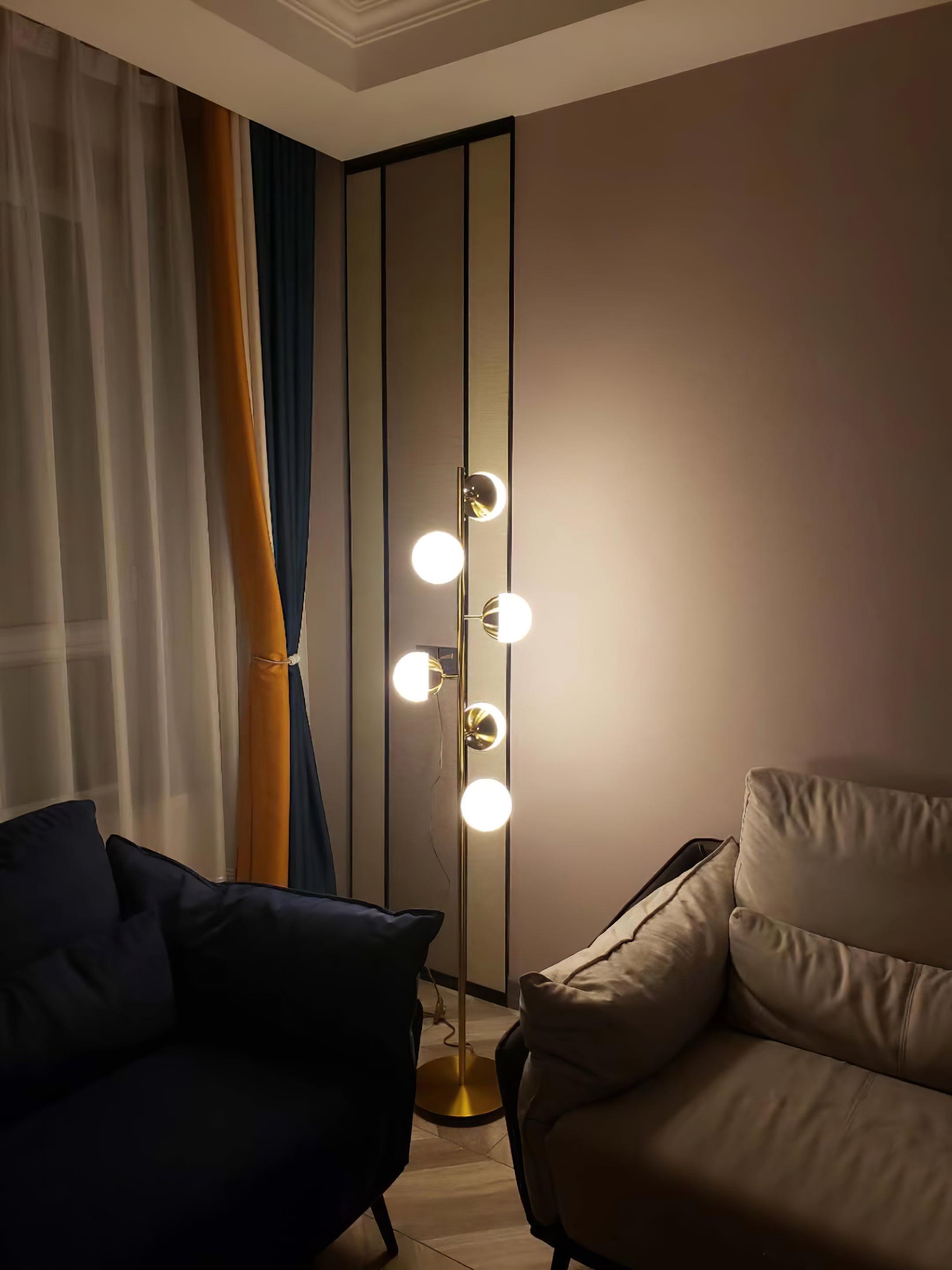 Tall gold globe lamp lit beside sofa