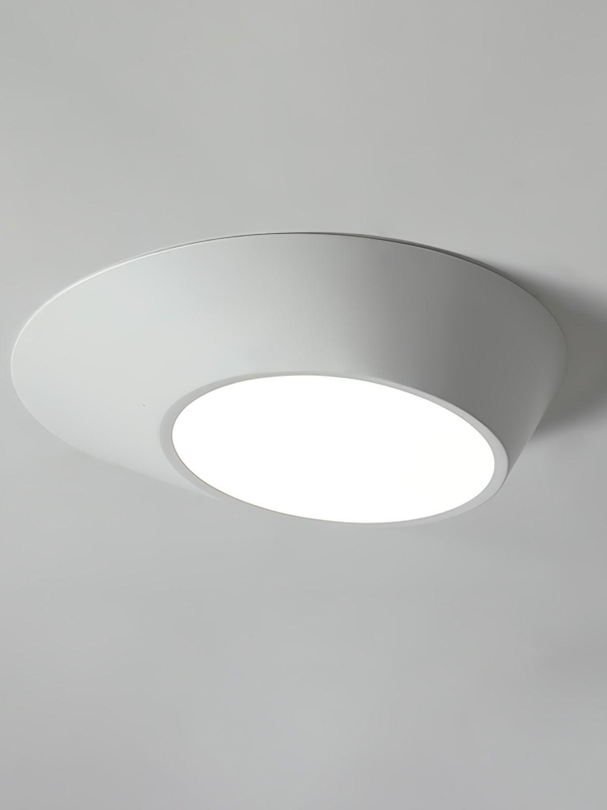 White angled ceiling light with a white-looking circular diffuser against a pale ceiling