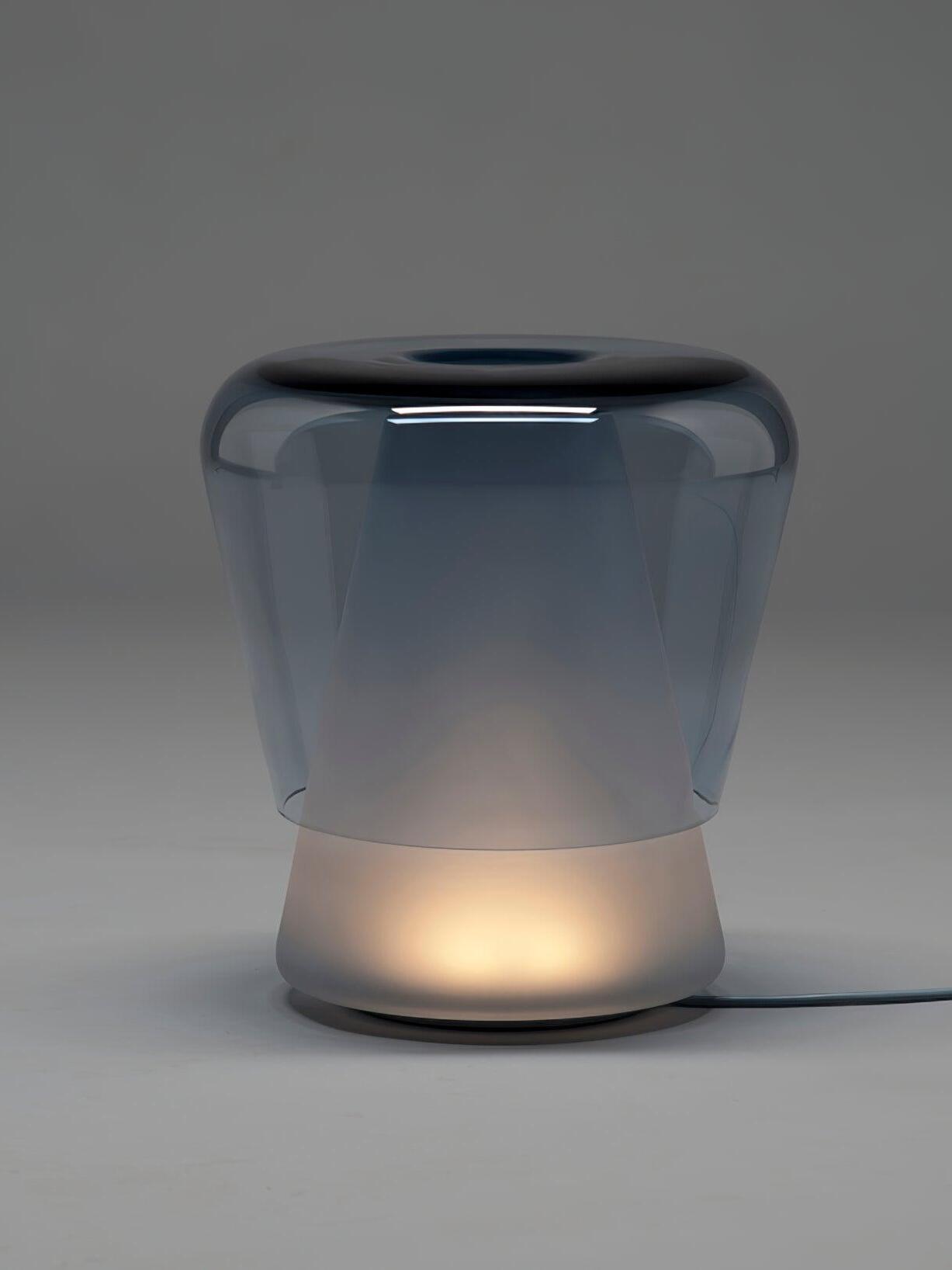 Blue Jumelle lamp lit near base on grey background