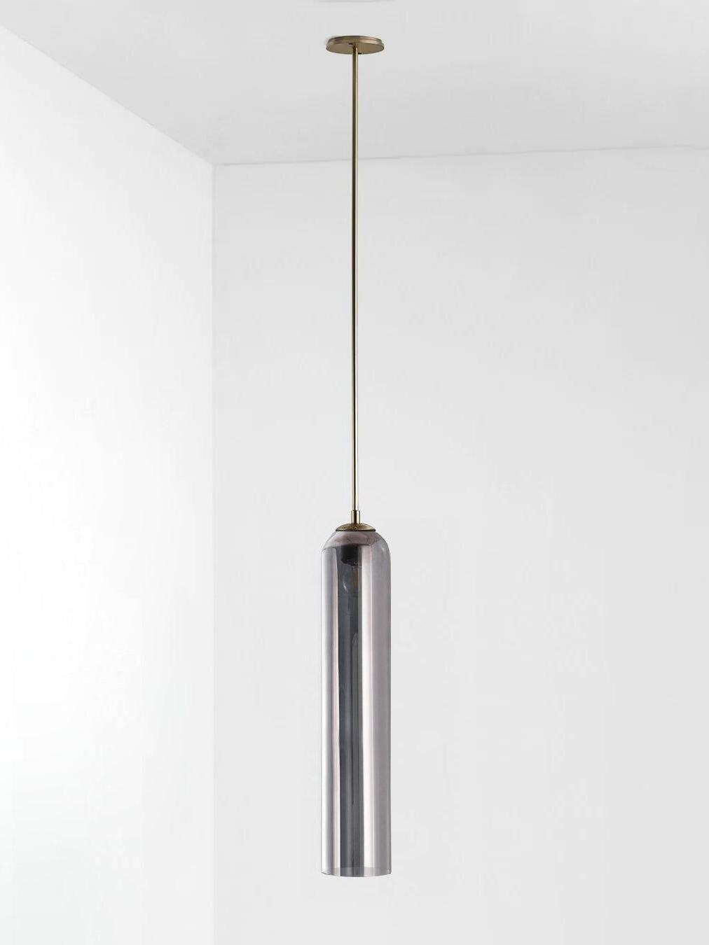 Silver gray glass Long Tube pendant with gold-toned rod and canopy, with reflections across the cylindrical shade