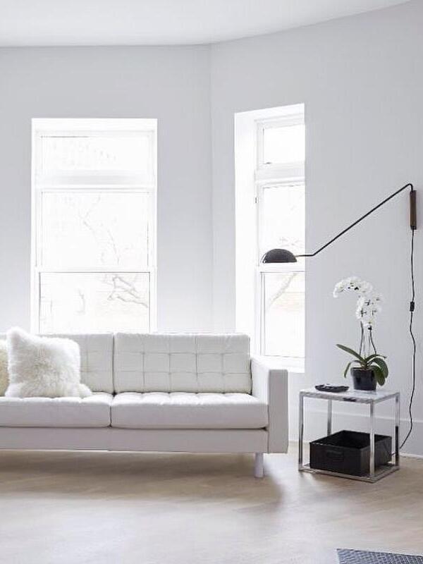 Black dome wall lamp above a white sofa and orchid side table, with wooden mount and hanging switched cord