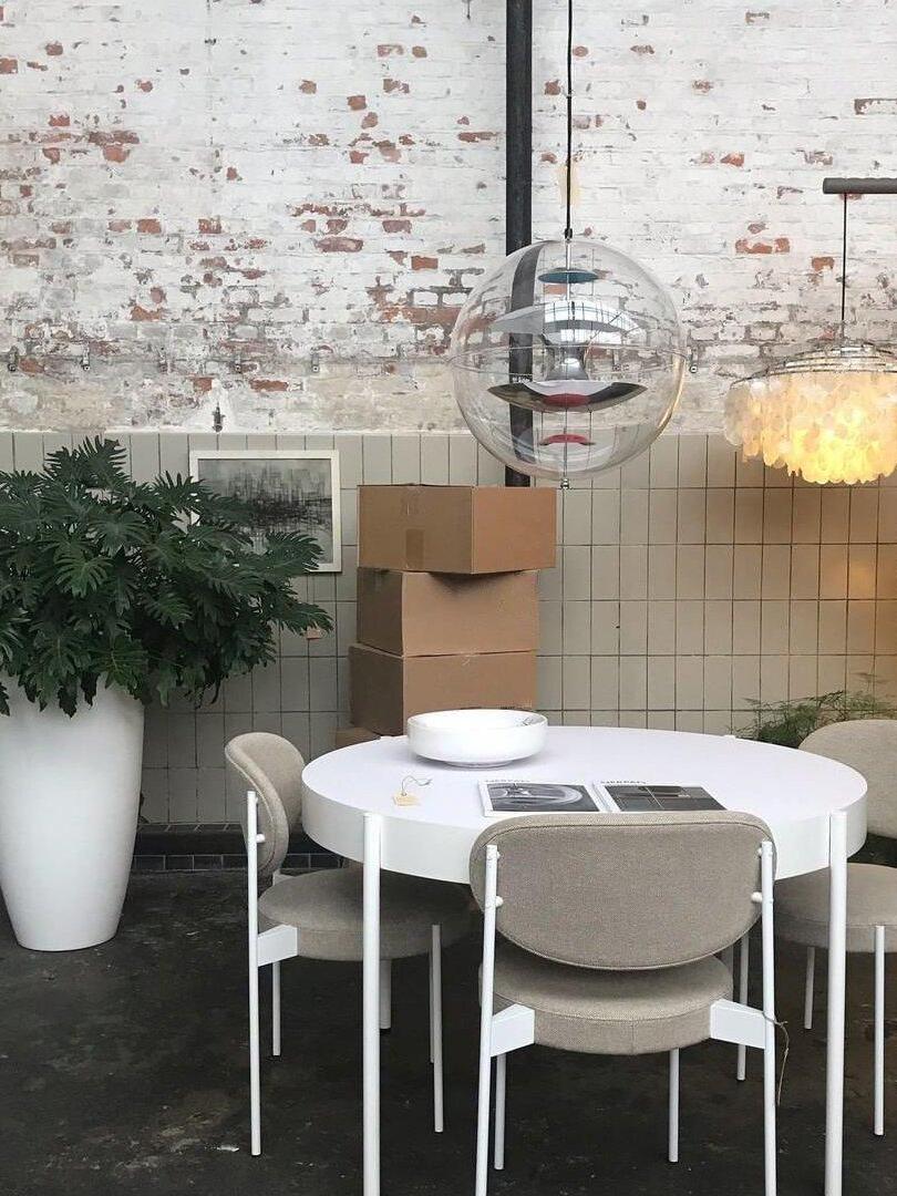 Clear reflector globe above a round white table against an exposed brick and tiled wall
