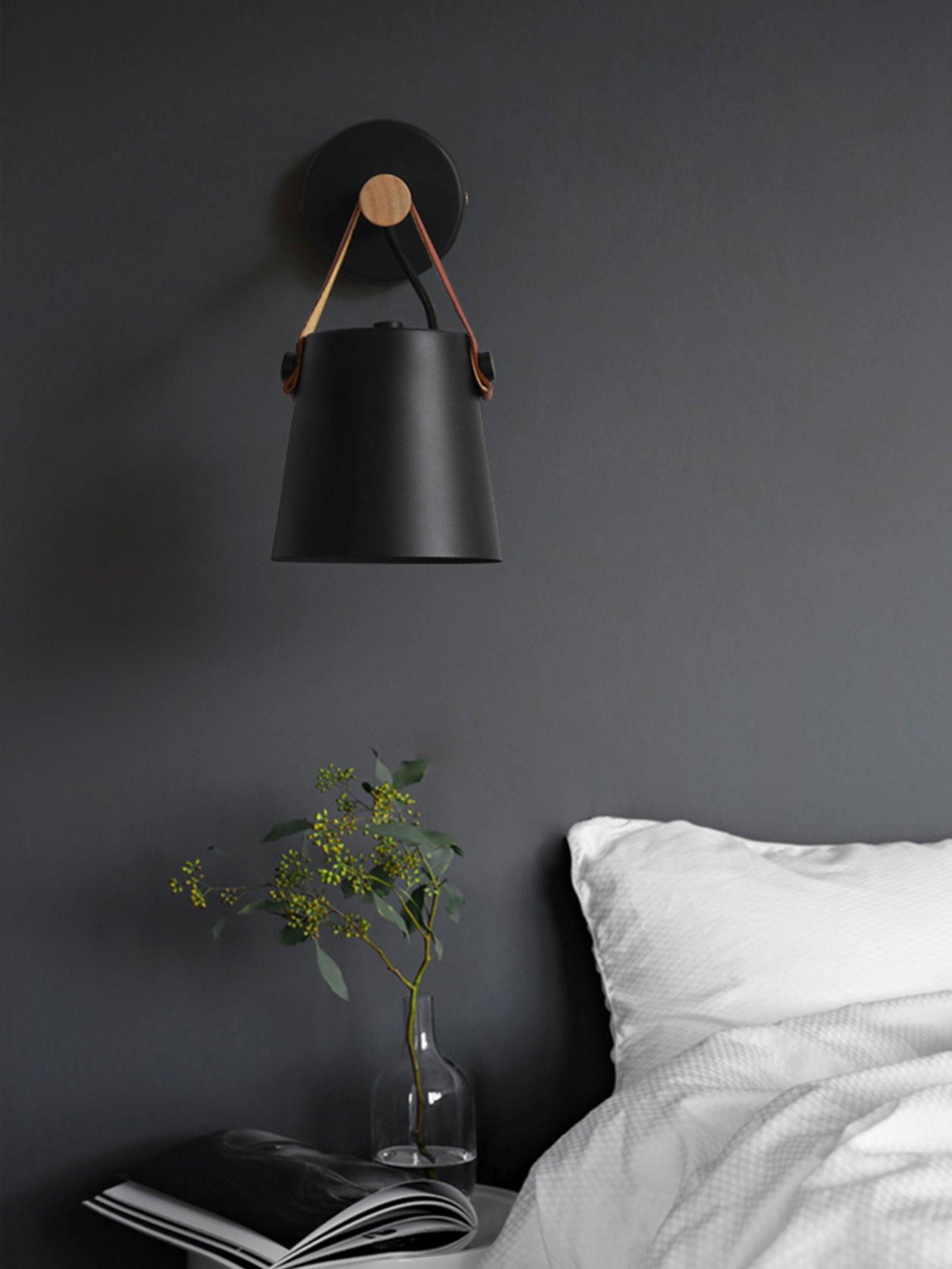 Black hanging wall light beside a bed