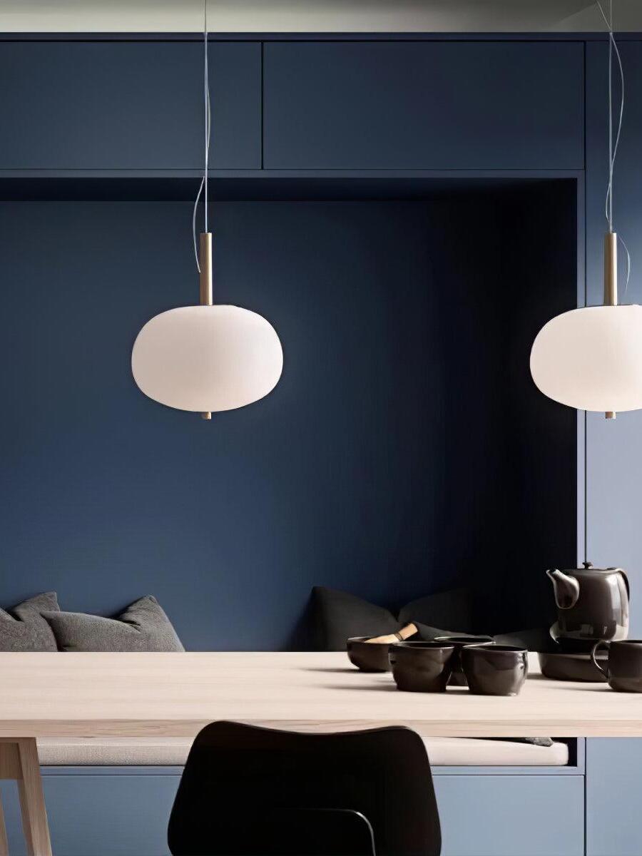 Two single-globe pendants against a blue wall