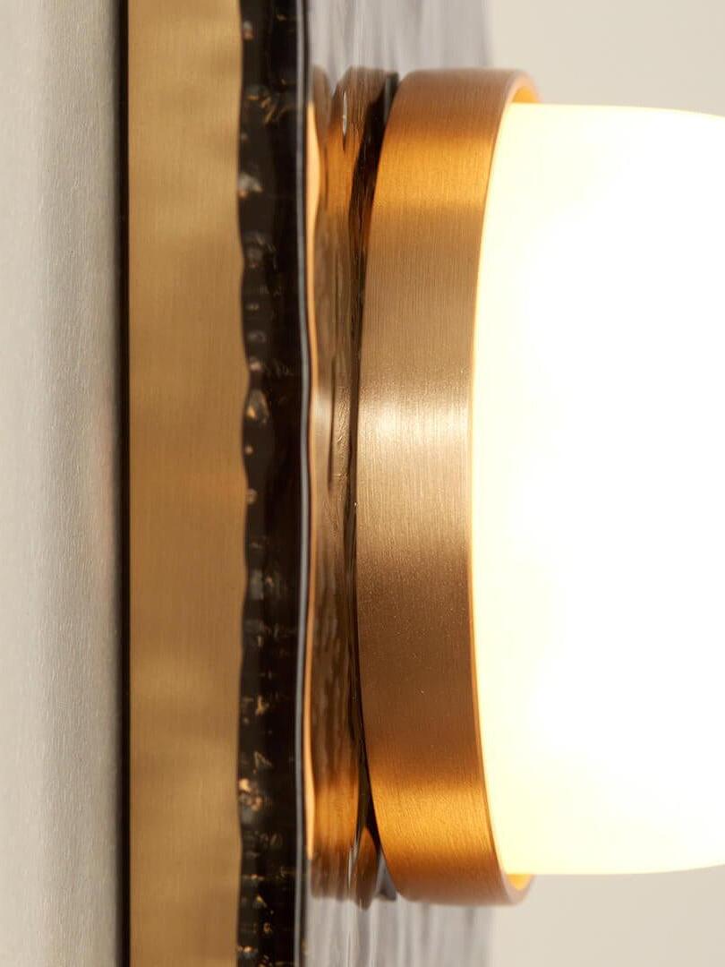 Side close-up of the Modulo dome and gold-tone rim beside the glass panel and wall fitting