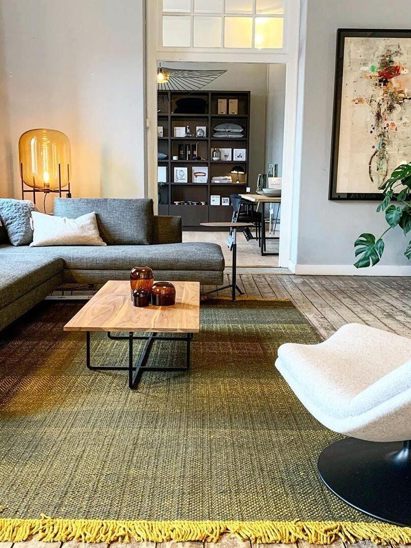 Amber glass lamp beside a dark sofa in a bright traditional living room.