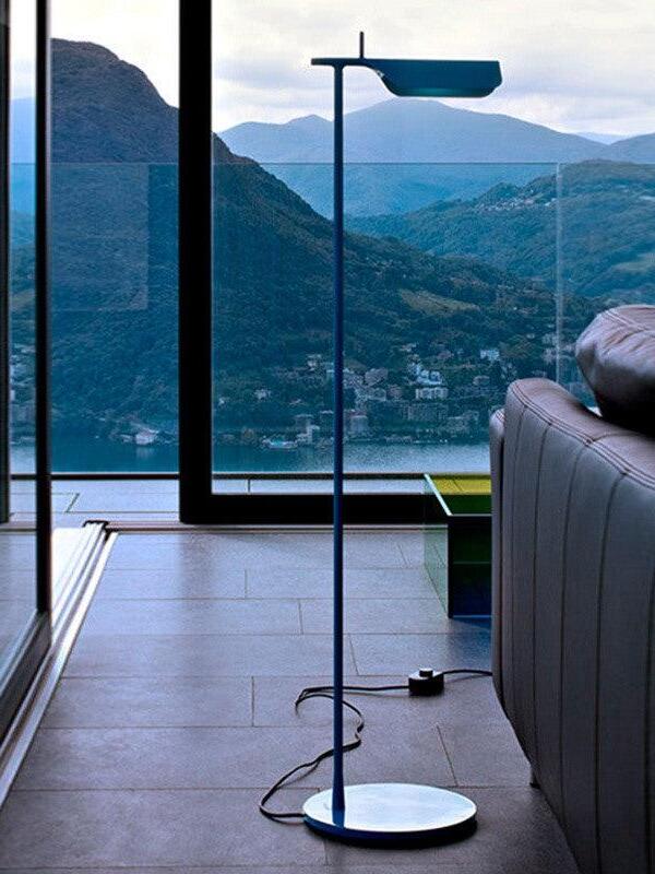 Blue floor lamp beside a window with its plug lead visible