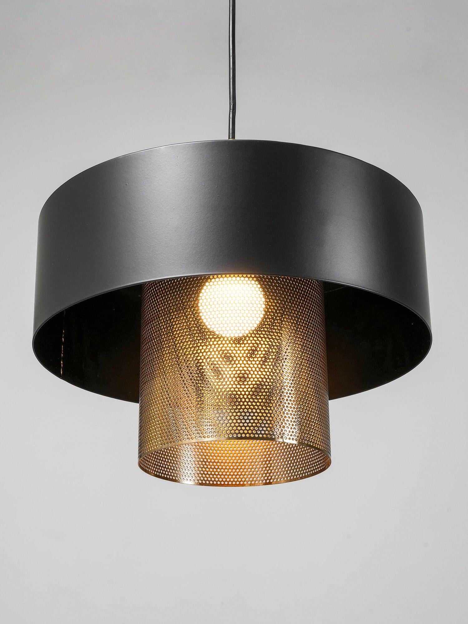Underside view of lit Bradbury pendant, showing a visible bulb behind the perforated copper-tone inner shade