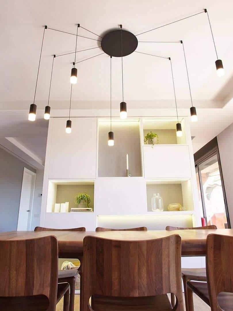 Black radial ceiling cables and hanging heads above wood dining chairs and display shelves