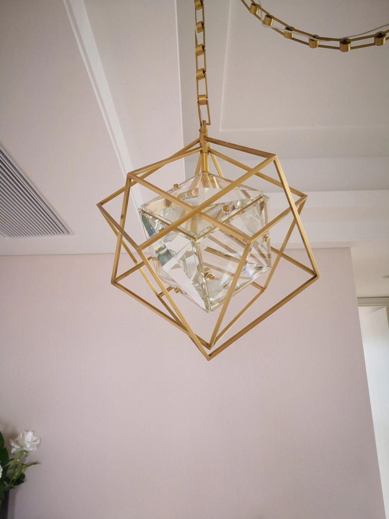 Angled view of an Epic pendant with brass-coloured frame, faceted inner shade and chain