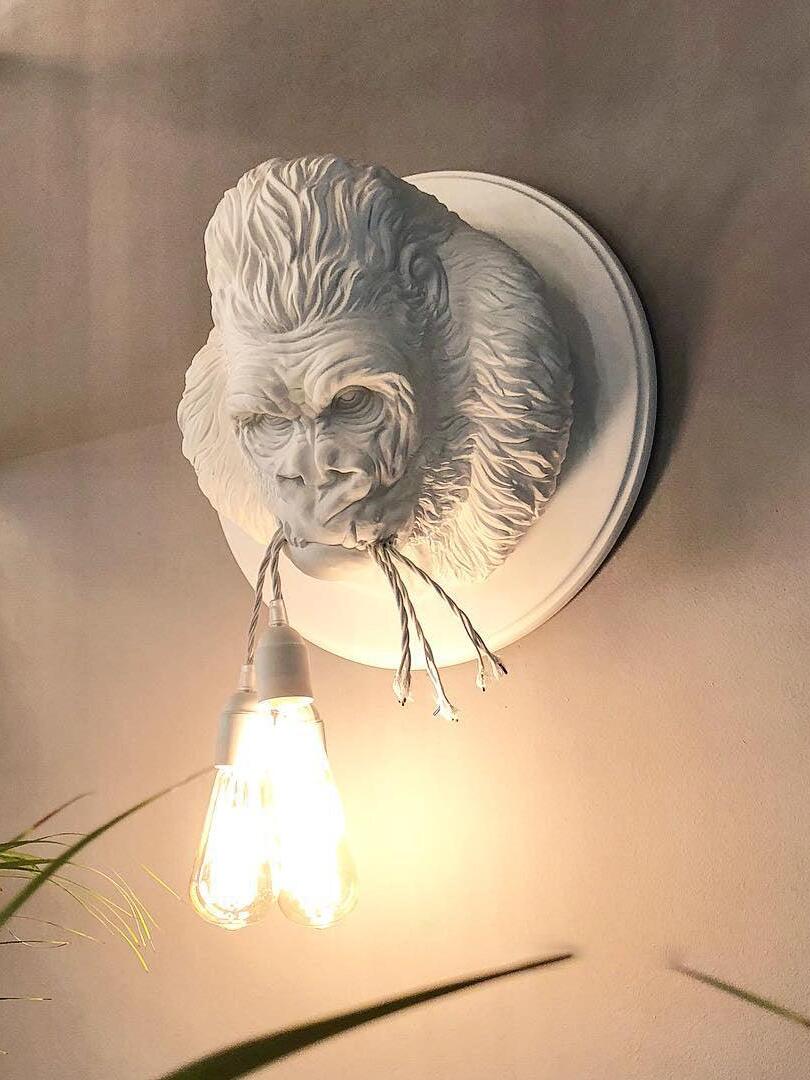 White gorilla relief with glowing exposed bulbs on warm-lit wall