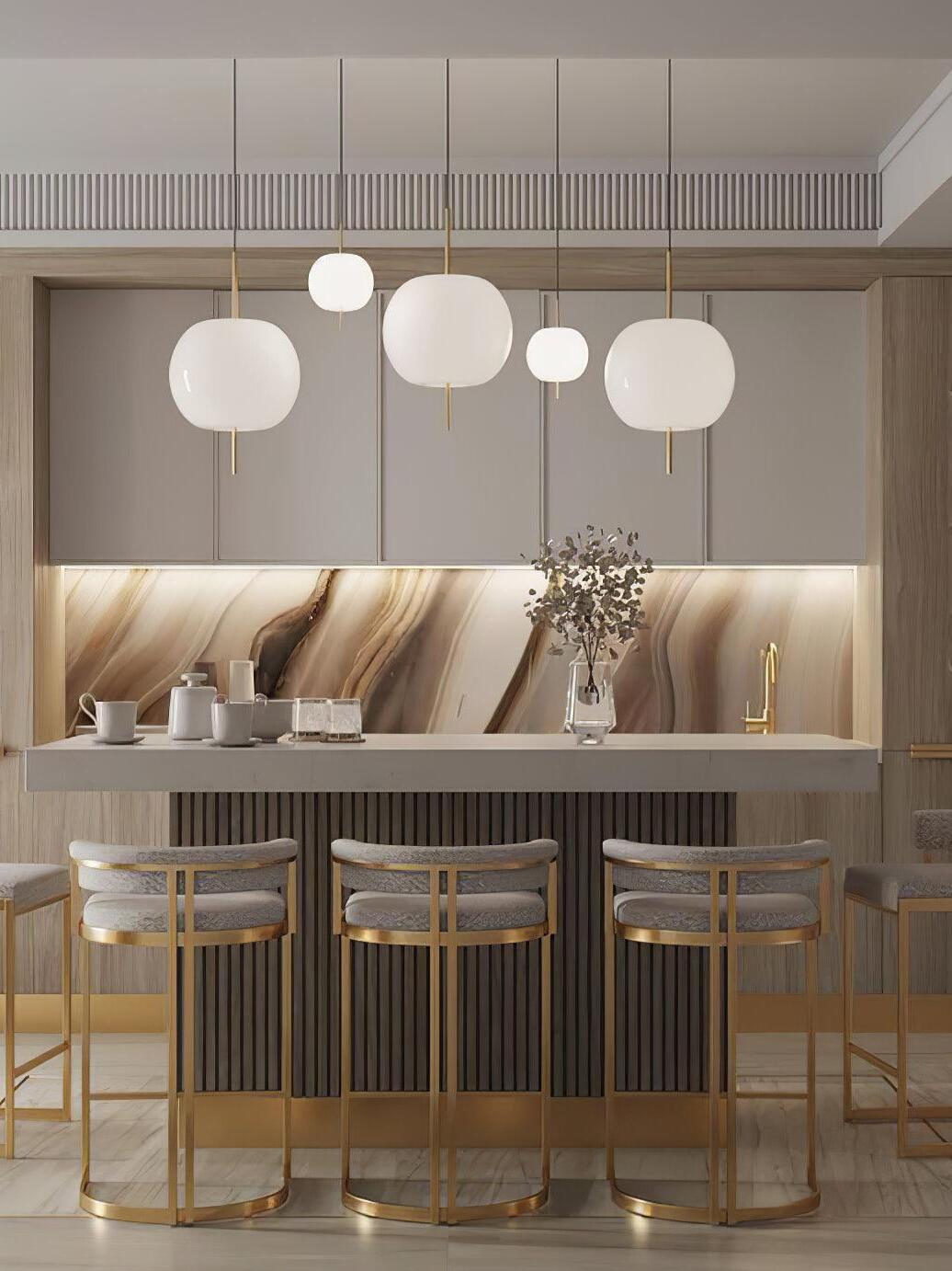 White glass pendants above a counter with gold-coloured stools