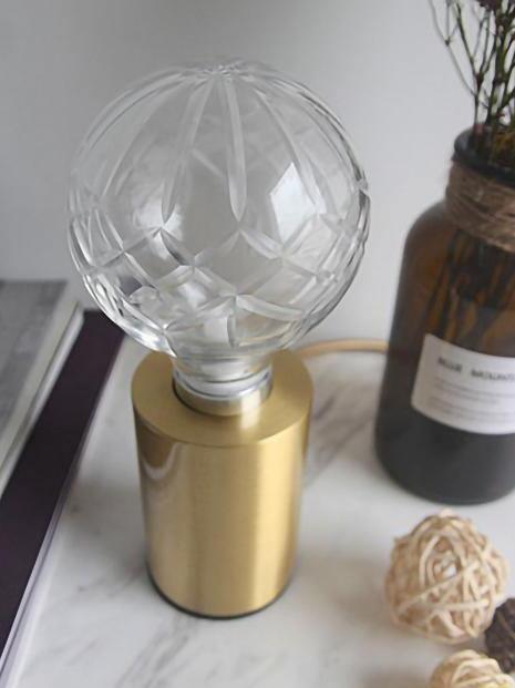 Top view of faceted glass globe lamp beside bottle and ornament