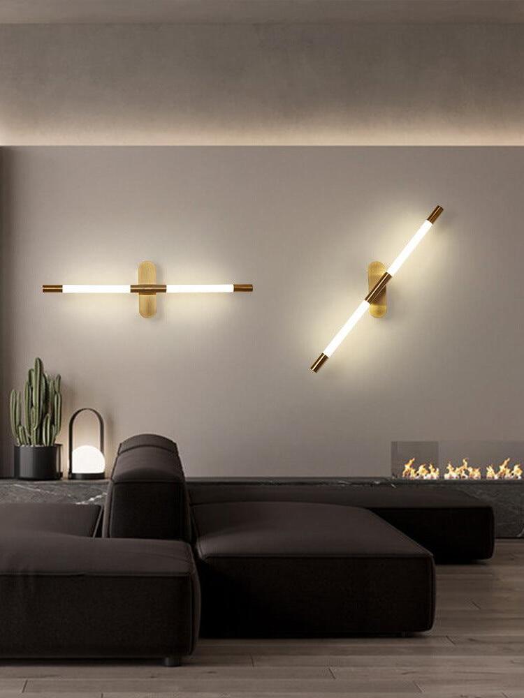 Two gold Agnes wall lights, one horizontal and one angled, above seating and a low flame feature