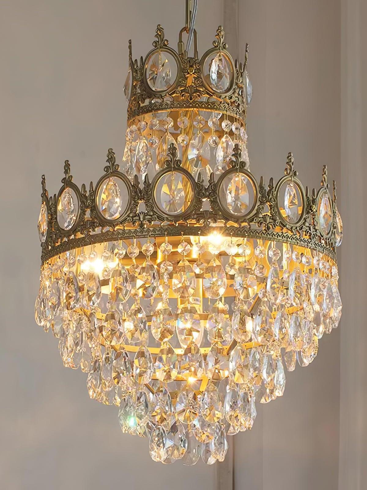 Close illuminated crystal chandelier showing round crown inserts and several rows of faceted hanging drops