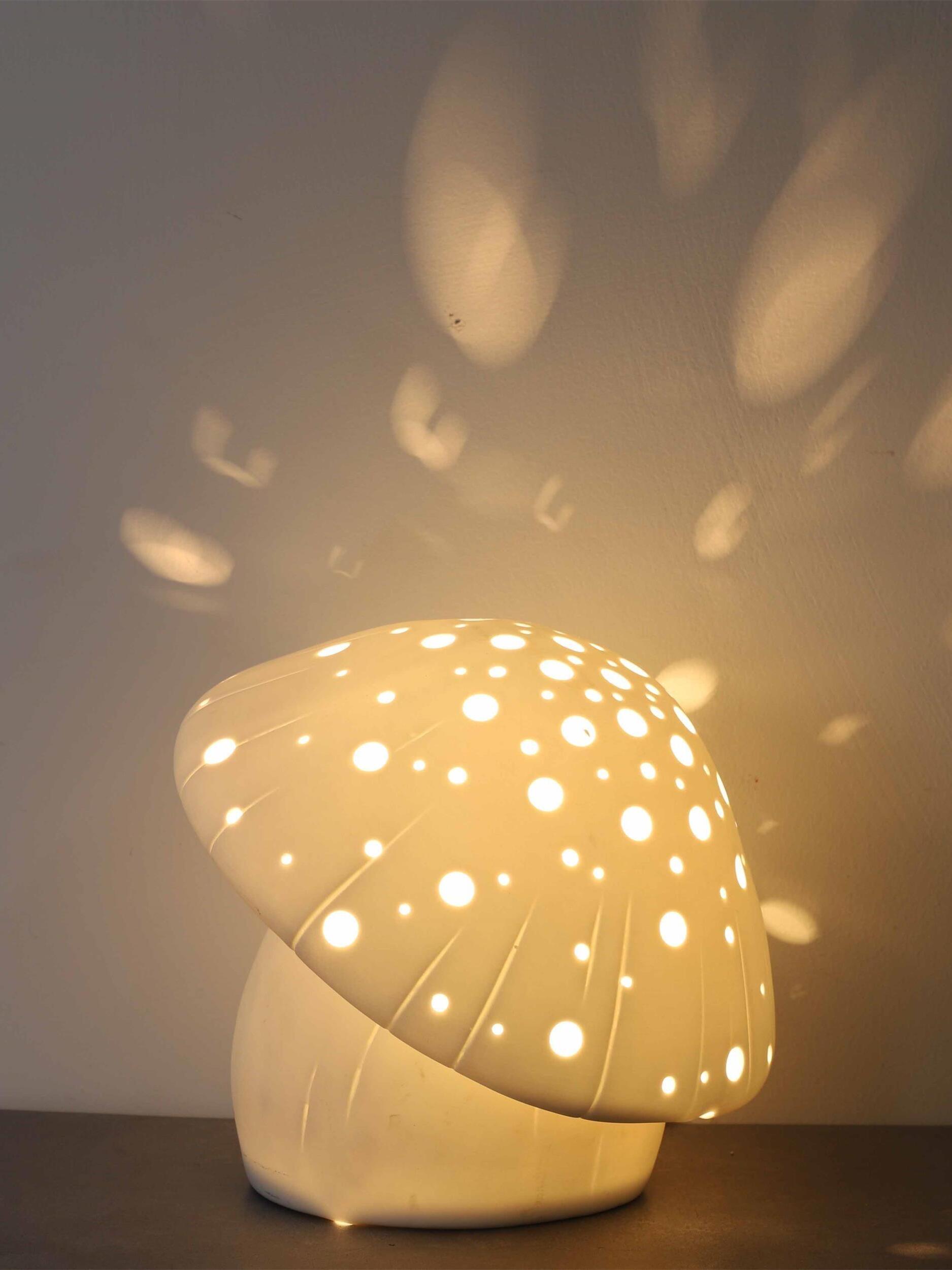 Front view of the illuminated tilted mushroom cap with light spots on a dark wall