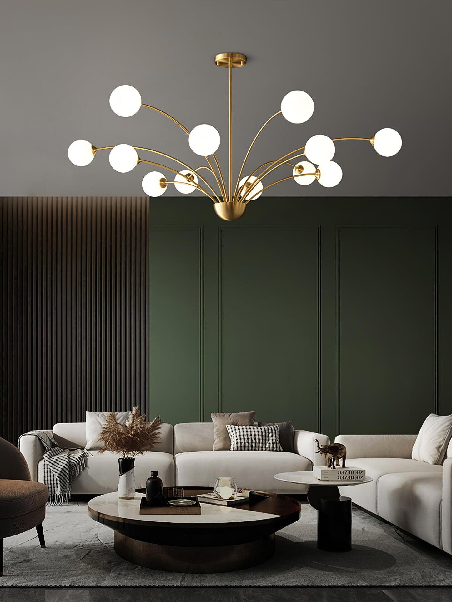 Wide white-globe chandelier above cream sofas and round coffee tables before green wall panels