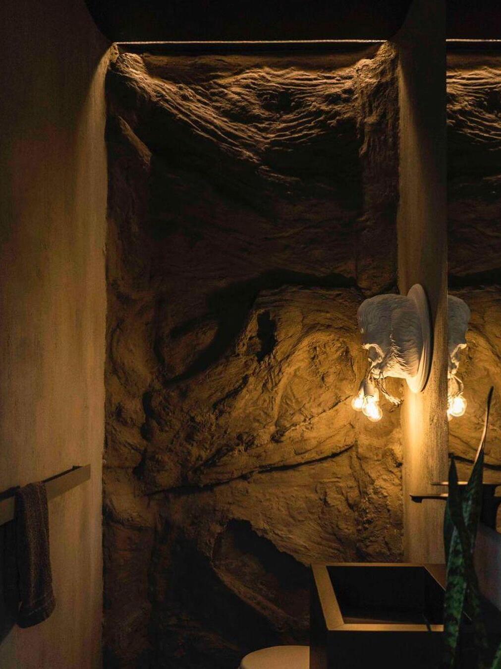 Darker wide washroom view with white gorilla light on pillar beside mirror