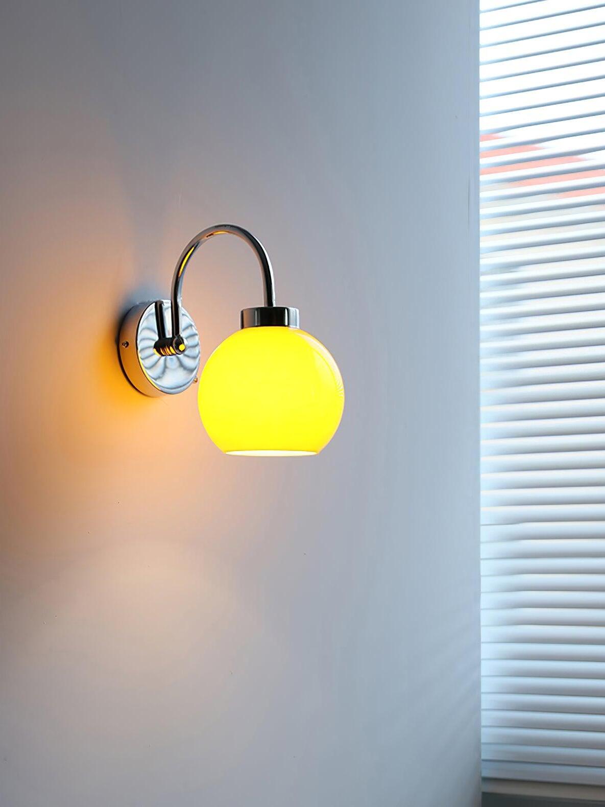 Small lit yellow-glowing globe below curved wall arm next to blinds